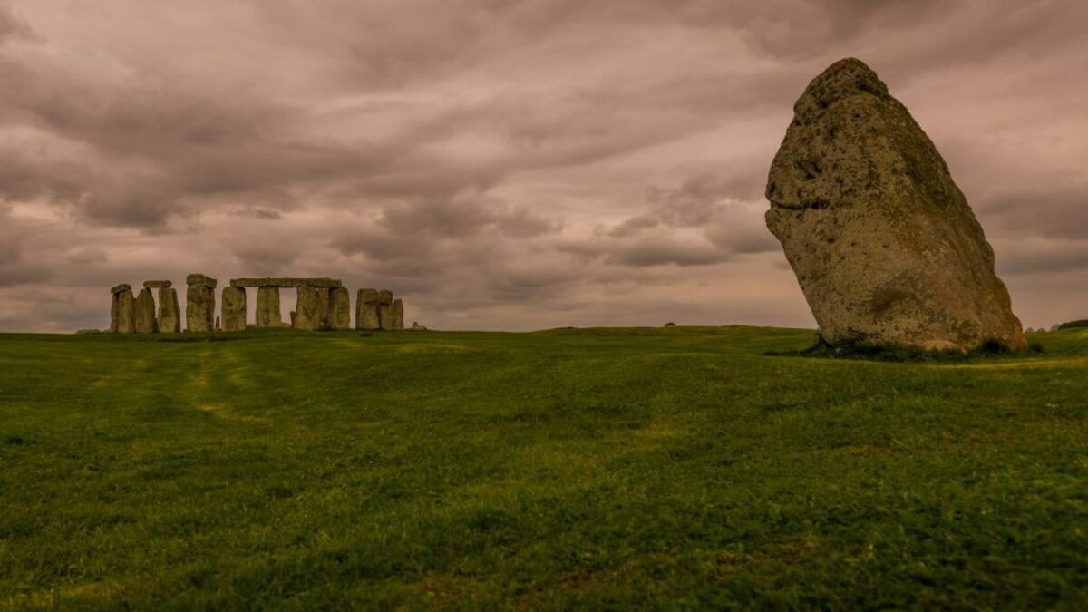 a large rock in the middle of a grassy field