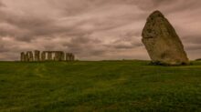 a large rock in the middle of a grassy field