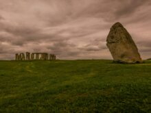 a large rock in the middle of a grassy field