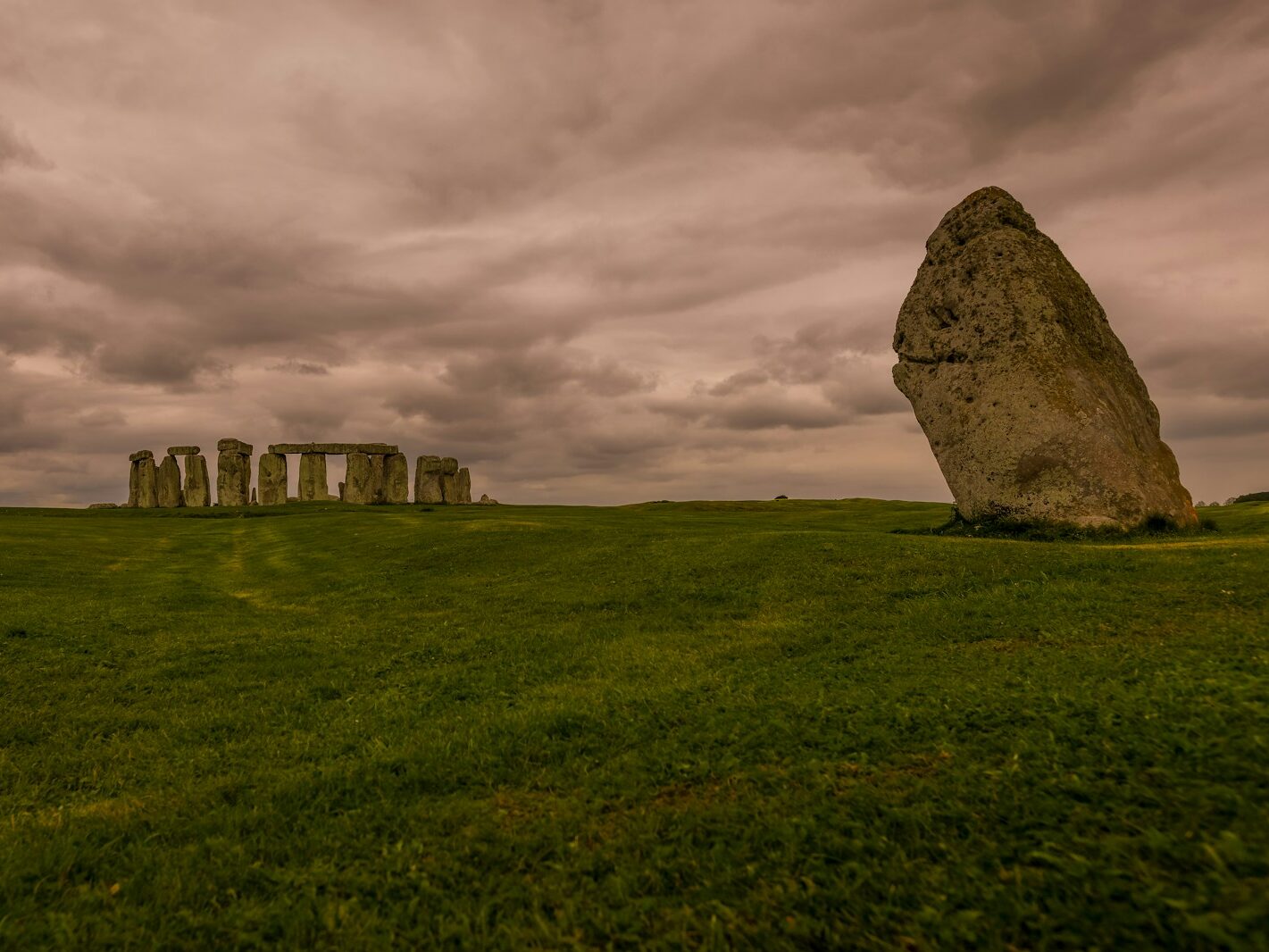 a large rock in the middle of a grassy field