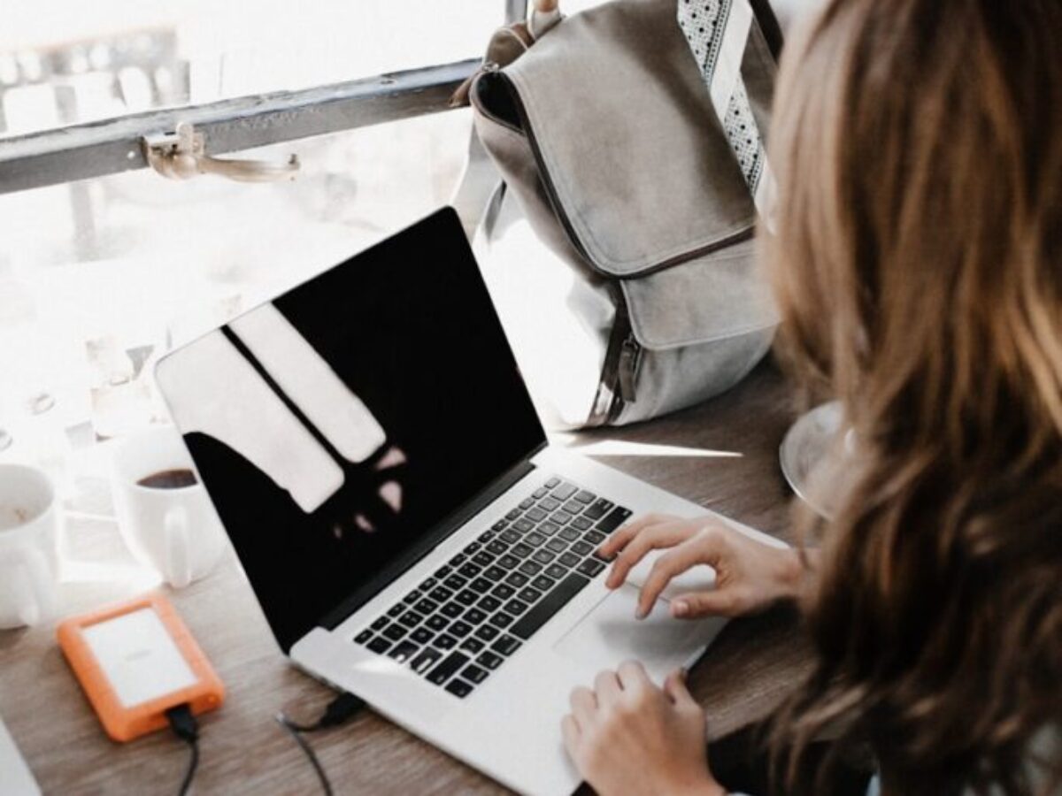 girl wearing grey long-sleeved shirt using MacBook Pro on brown wooden table