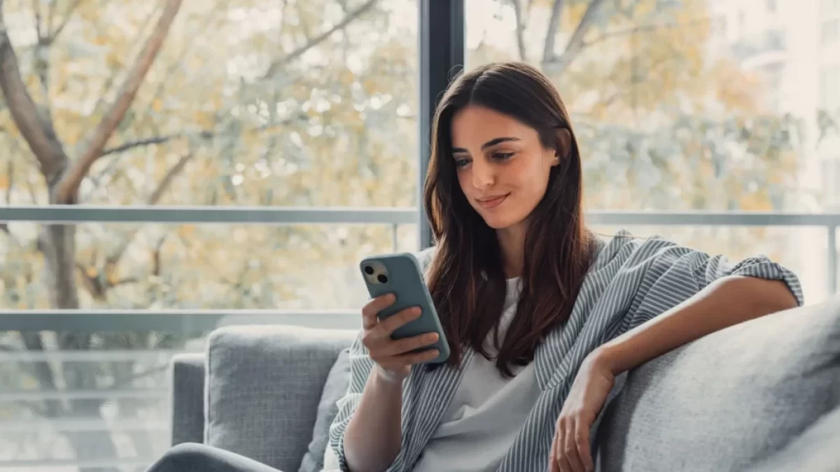 Žena na gauči s mobilním telefonem