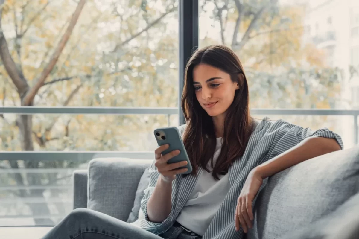 Žena na gauči s mobilním telefonem