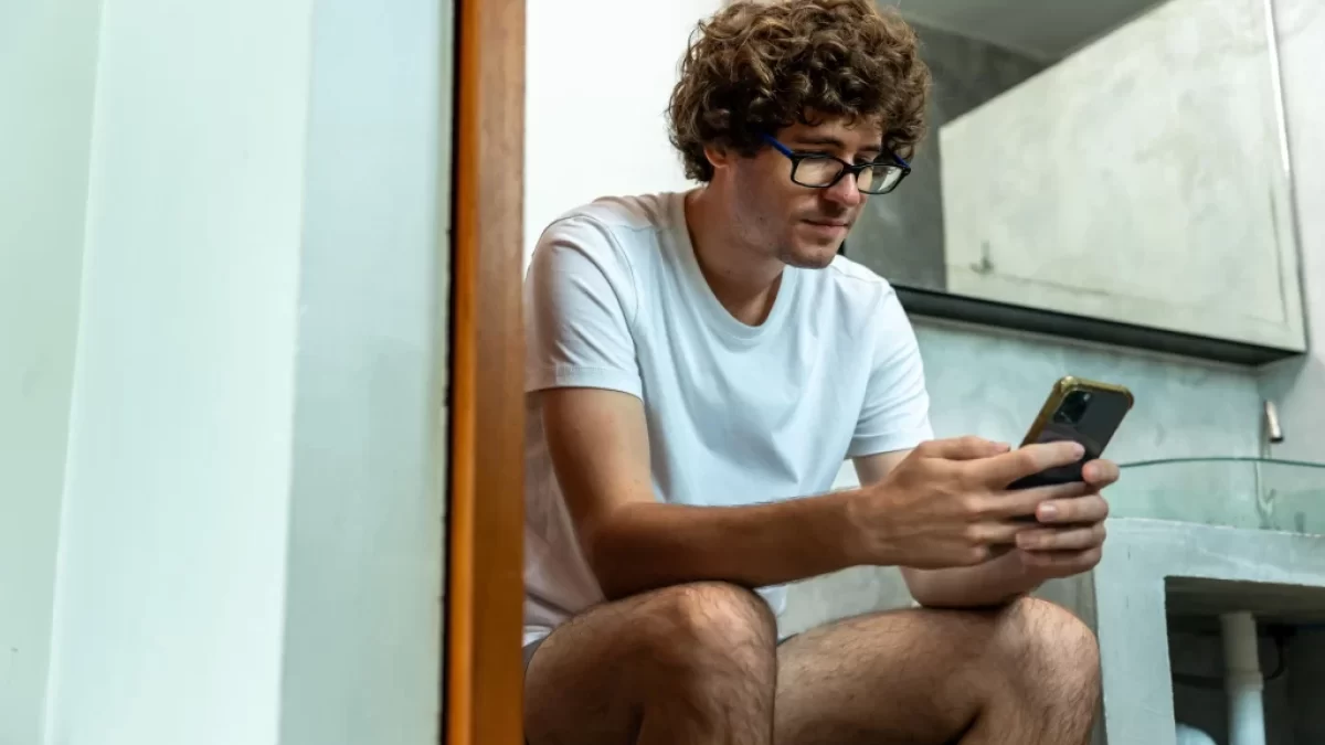 muž na wc s mobilem v ruce