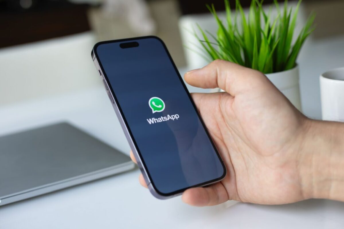 Ruka drží mobilní telefon, na kterém se spouští aplikace WhatsApp