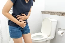 Žena s bolestmi břicha u toalety