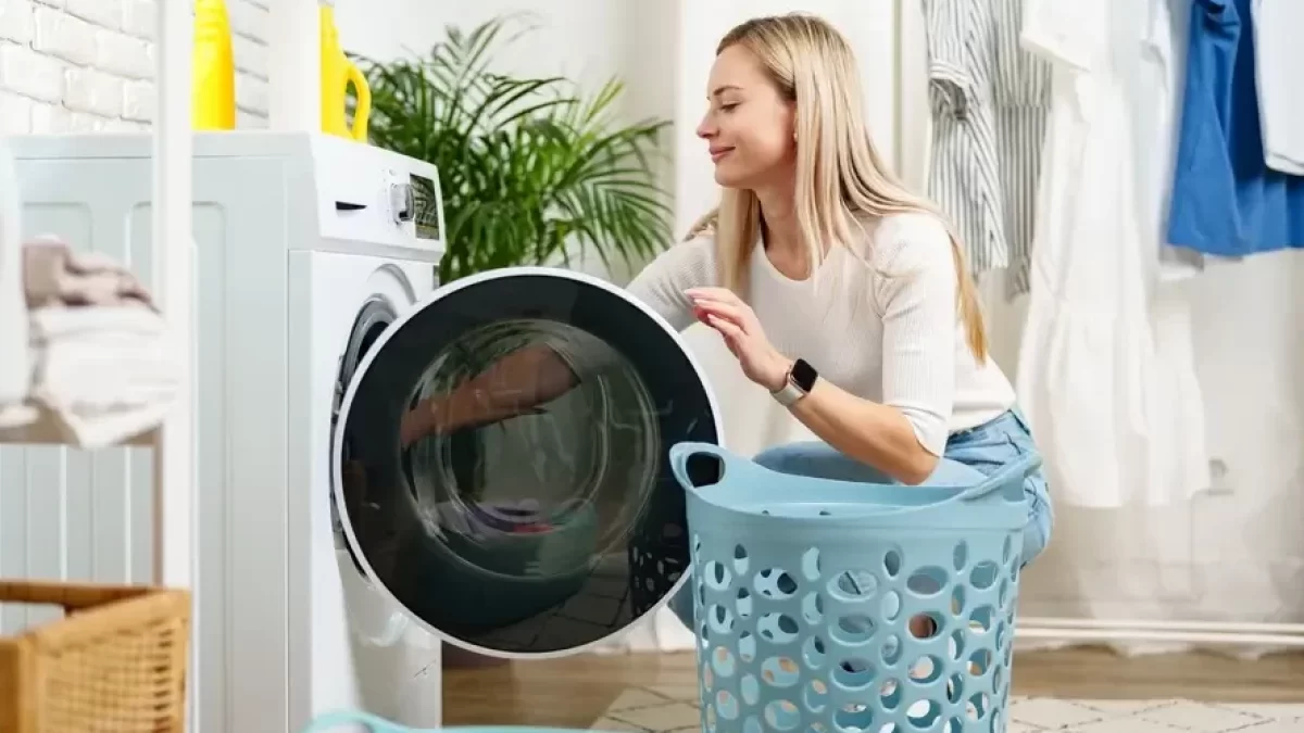 Žena vytahuje prádlo z pračky.
