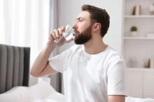 Muž pijící vodu z kohoutku