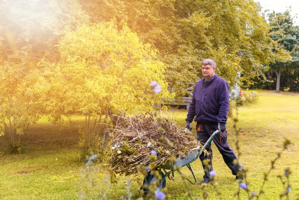 Muž s kolečky listí na zahradě
