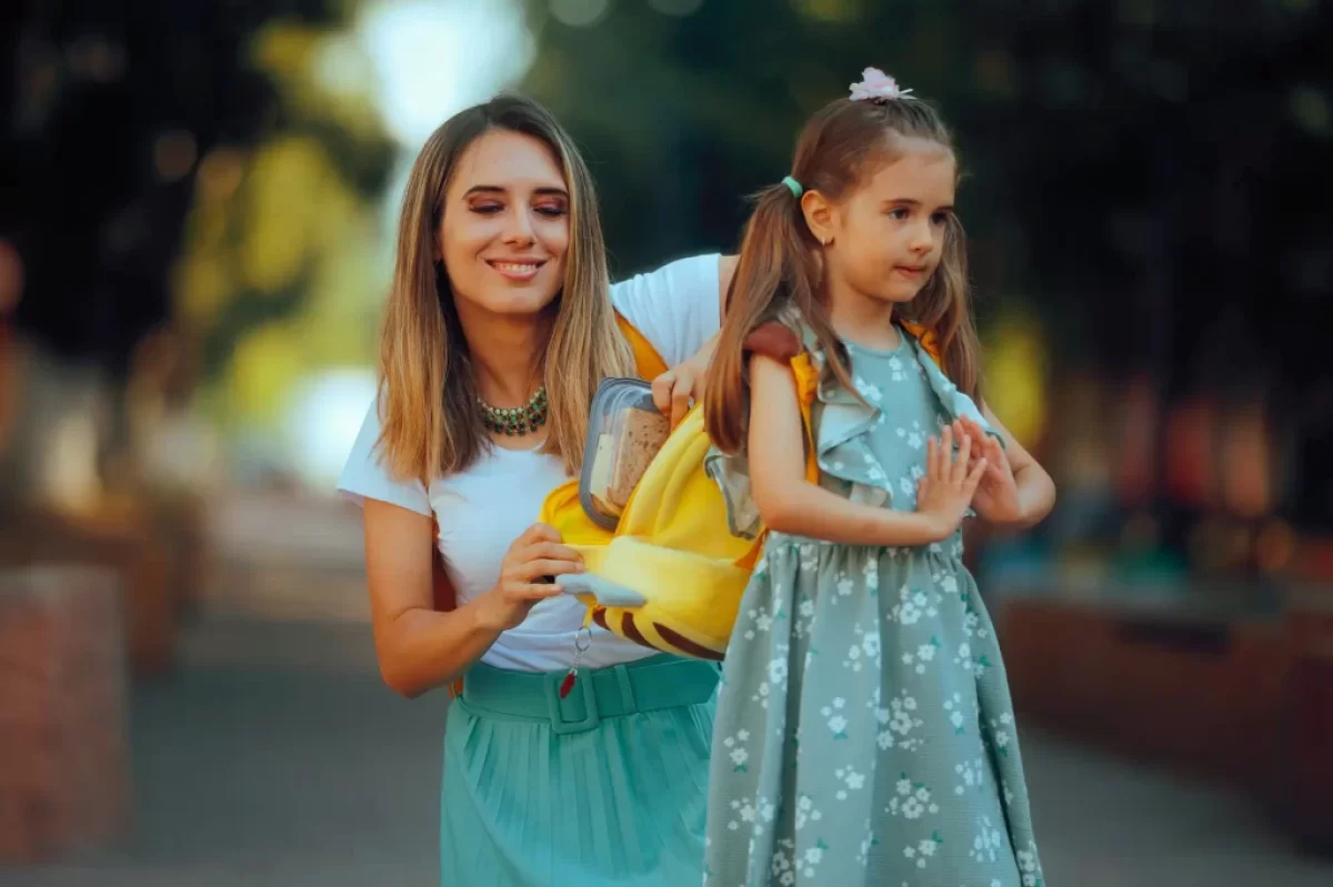 Matka dává dceři do batohu svačinu