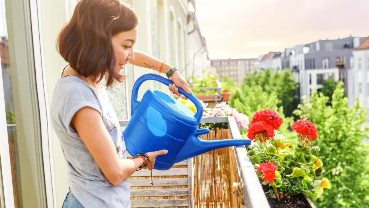 Žena, která zalévá květiny na balkoně