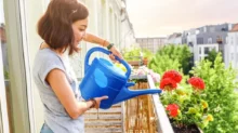 Žena, která zalévá květiny na balkoně
