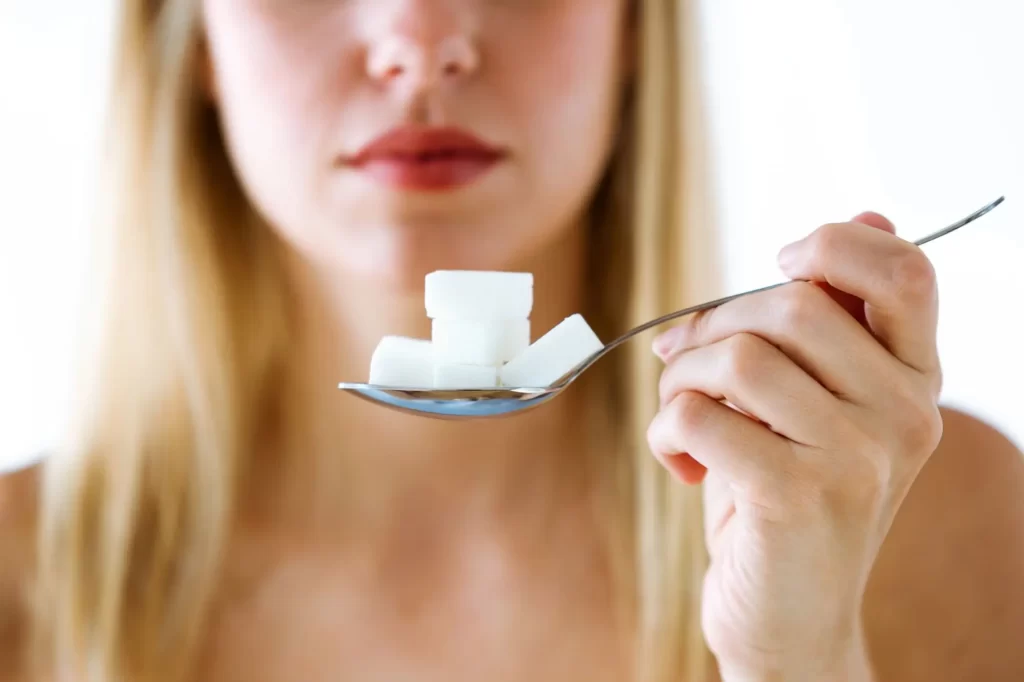 Shutterstock_1217732002 - Techsvět Žena drží na lžičce několik kostek cukru