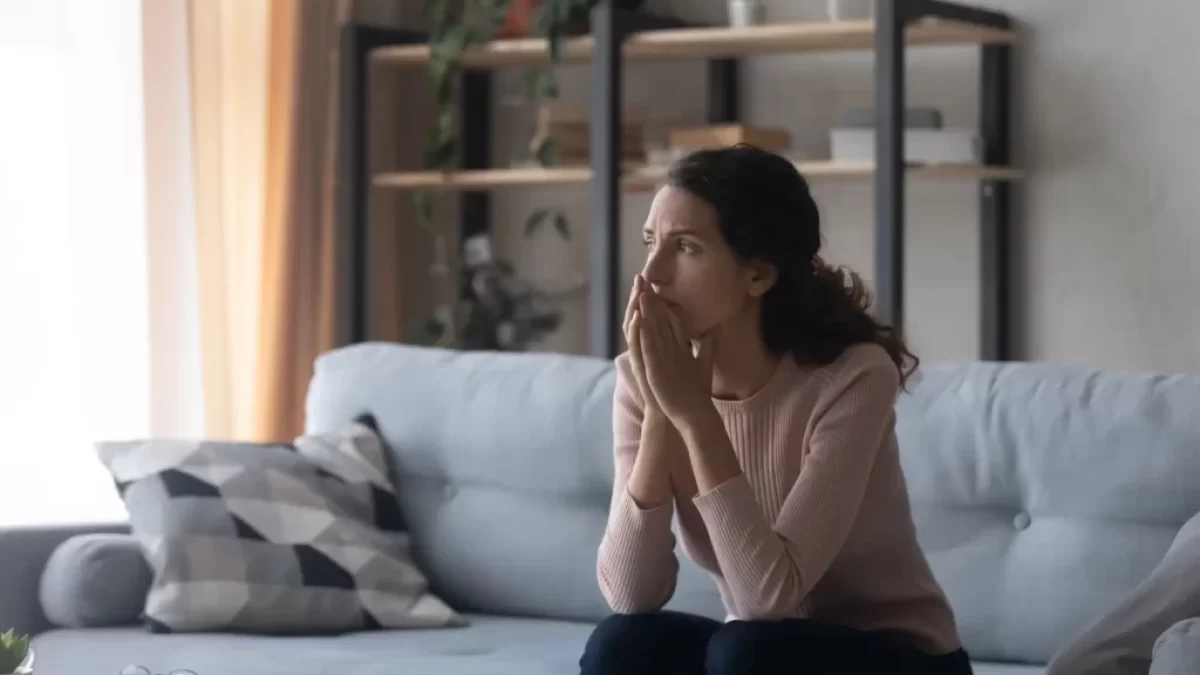 žena sedí na gauči a přemýšlí