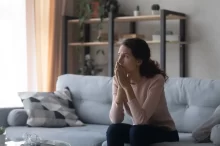 žena sedí na gauči a přemýšlí