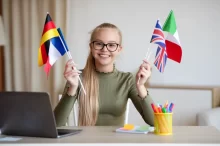 polyglotka, dívka sedí u počítače s různými vlajkami v rukou