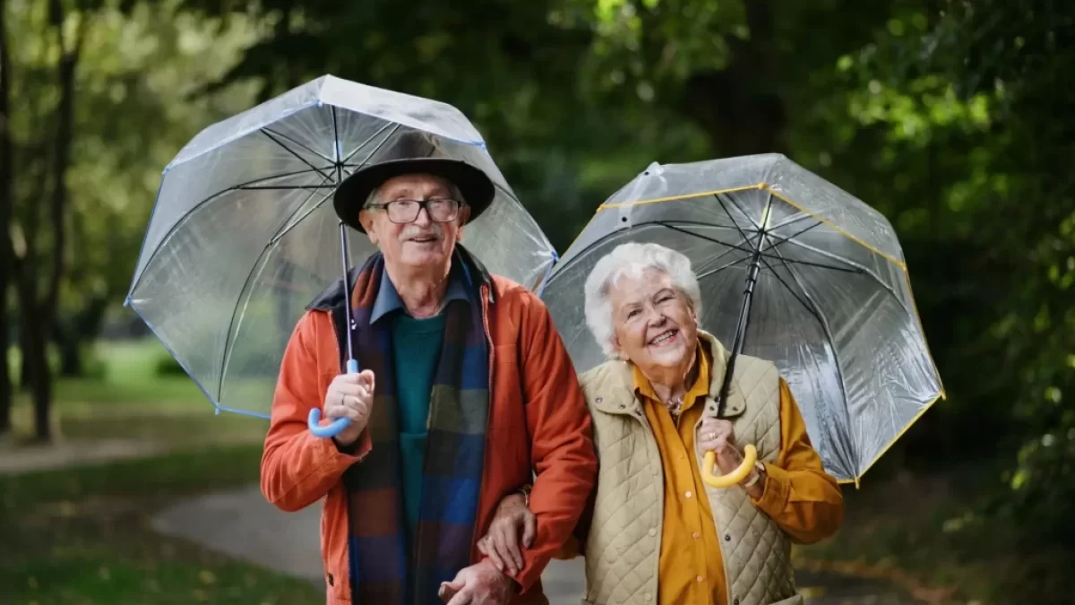 seniorský pár na procházce s deštníky