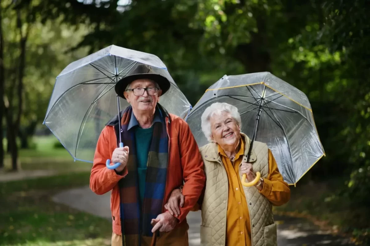 seniorský pár na procházce s deštníky