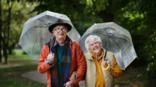 seniorský pár na procházce s deštníky