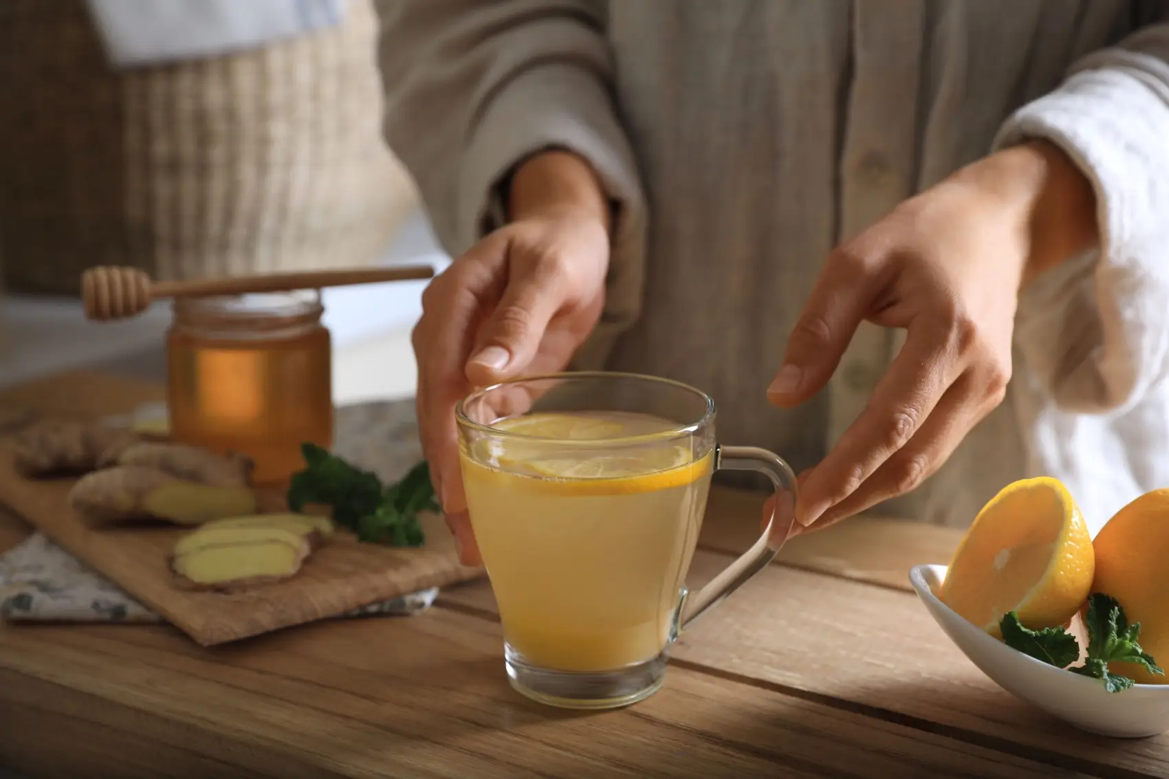 Žena připravuje horký nápoj ze zázvoru a citronu