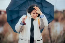 Žena jde s deštníkem proti větru
