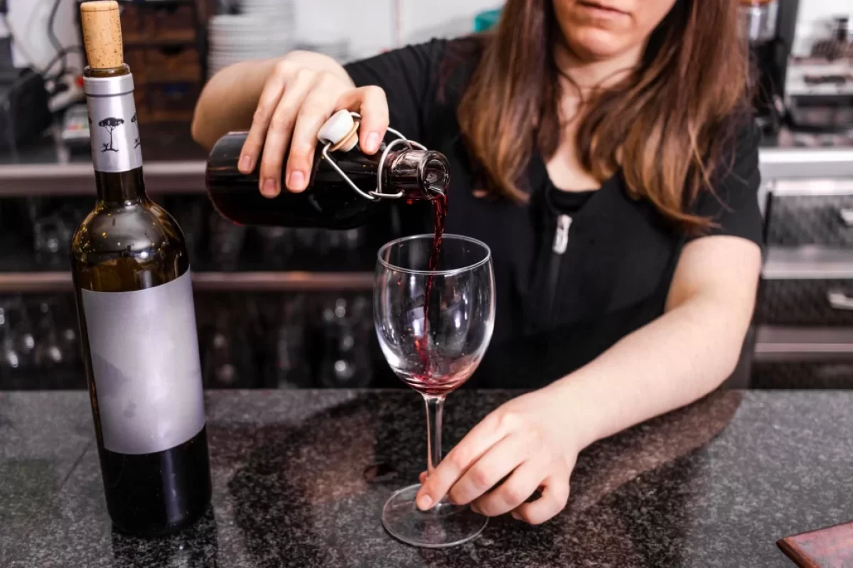 žena si v kuchyni nalévá červené víno