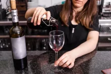 žena si v kuchyni nalévá červené víno