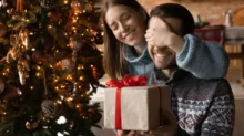 Žena dává dárek svému partnerovi u vánočního stromku