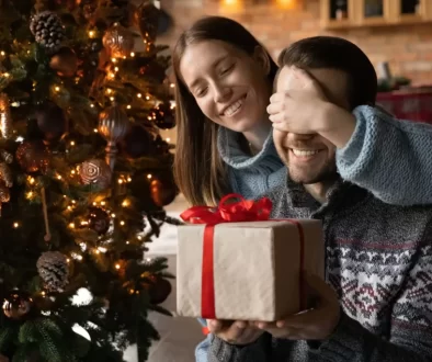 Žena dává dárek svému partnerovi u vánočního stromku