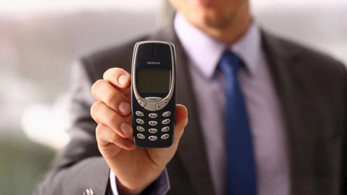 muž v obleku drží v ruce telefon nokia 3310