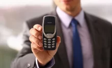 muž v obleku drží v ruce telefon nokia 3310