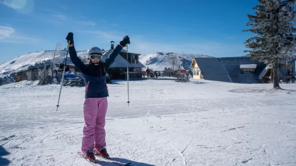 Žena s lyžemi stojící uprostřed ski areálu