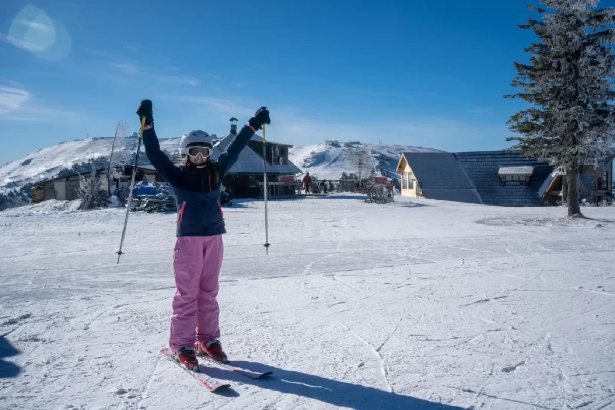 Žena s lyžemi stojící uprostřed ski areálu