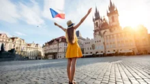Mladá žena v šatech drží českou vlajku