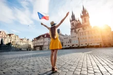 Mladá žena v šatech drží českou vlajku
