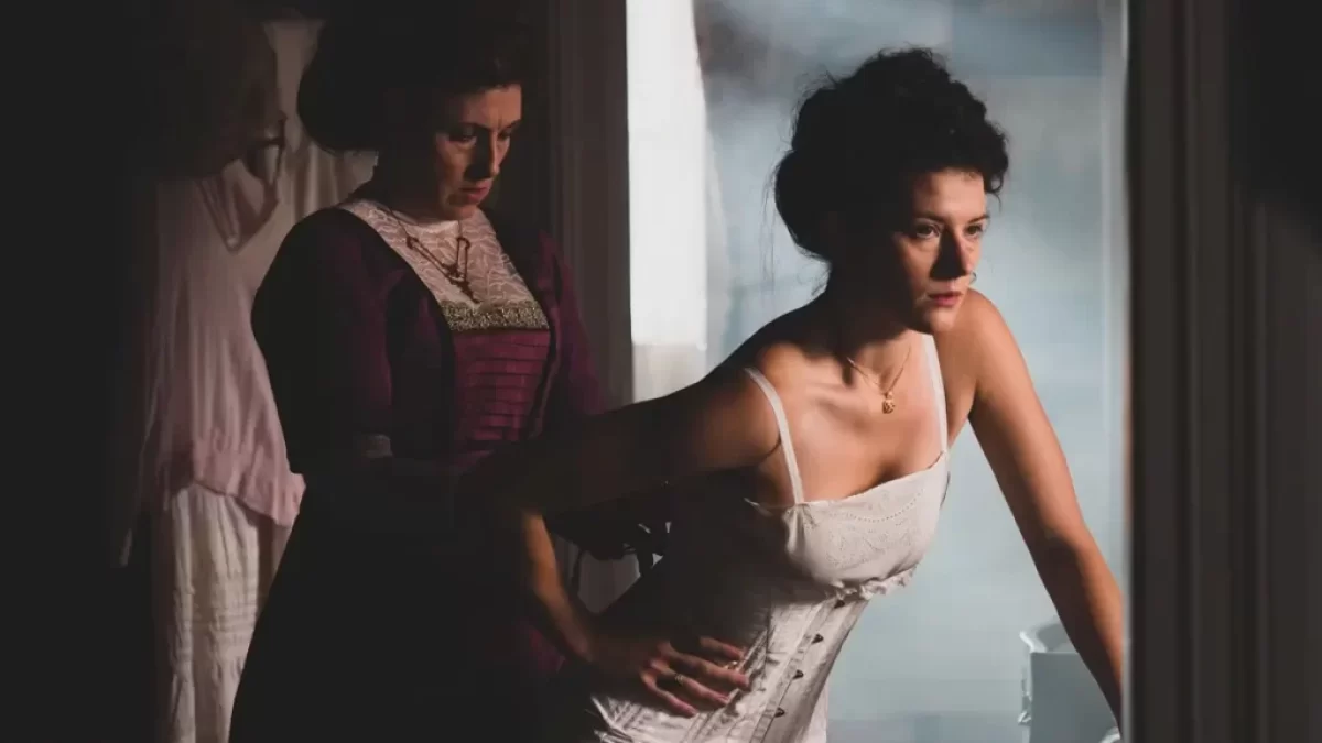 Žena se nechá navlékat do korzetu