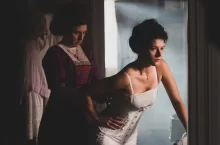 Žena se nechá navlékat do korzetu