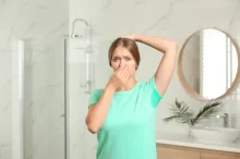 žena v koupelně se drží za nos