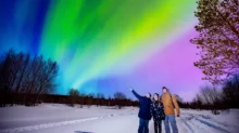 trojice lidí obdivuje polární záři
