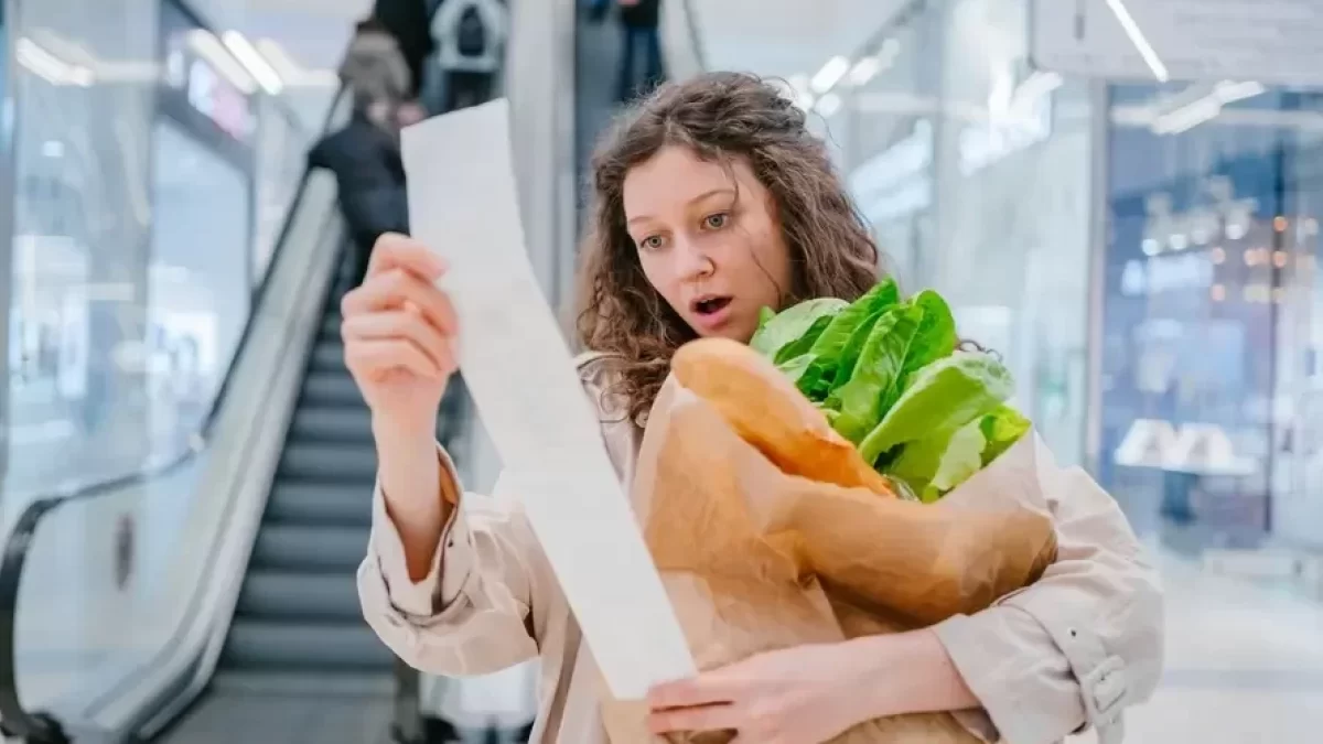 Zděšená žena čte ceny na lístku z pokladny