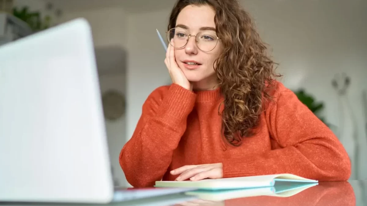 Žena s brýlemi se dívá do laptopu.