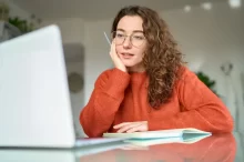Žena s brýlemi se dívá do laptopu.