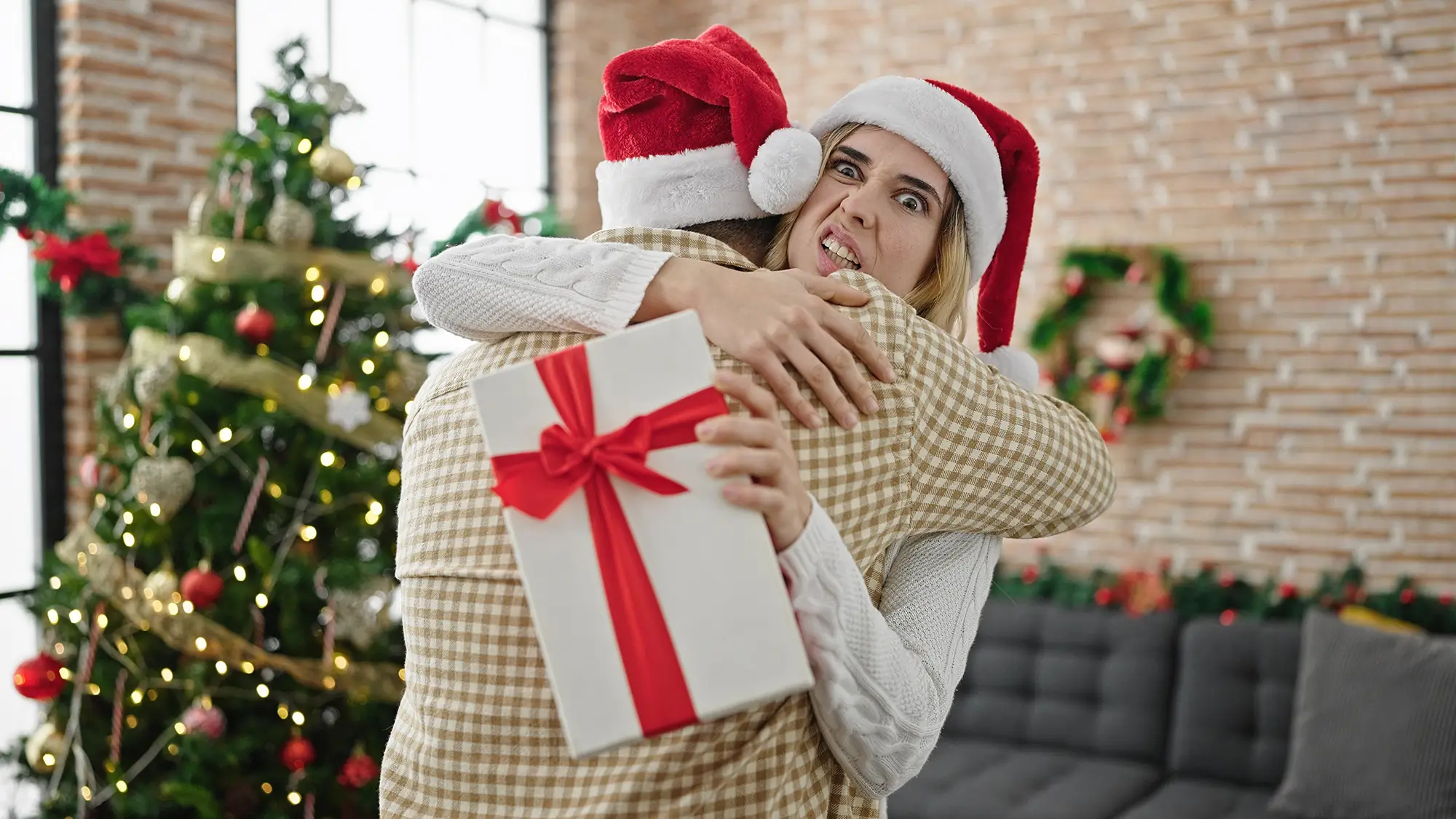 žena objímá partnera, ale šklebí se nad dárkem