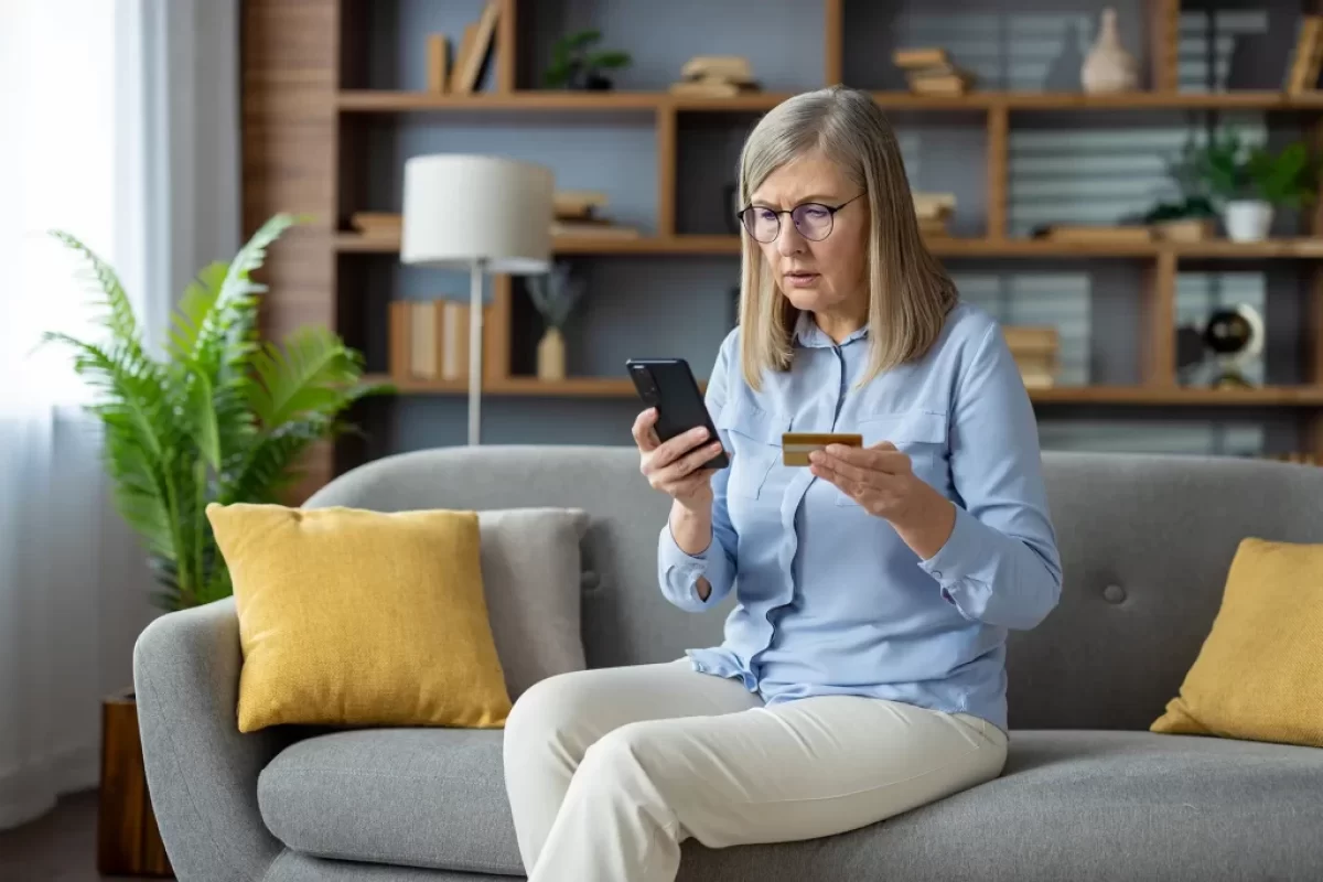 vyděšená žena s telefonem a platební kartou v ruce