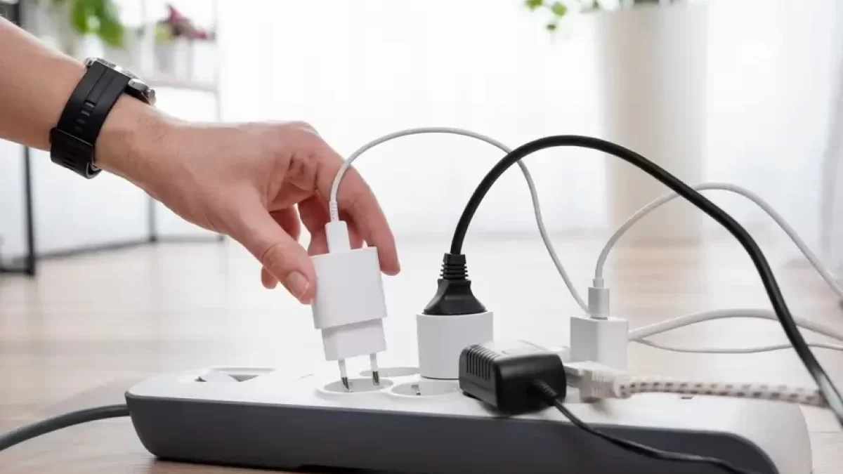 ruka zapojuje kabely do prodlužovací zásuvky