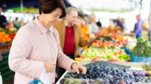 Žena na tržnici vybírá ovoce, které si koupí.