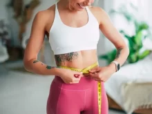 Žena si spokojeně měří shozená kila metrem kolem břicha