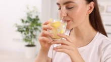 Žena, která pije vodu s citrónem.