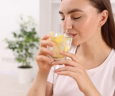 Žena, která pije vodu s citrónem.