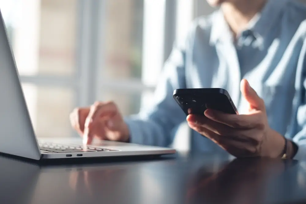 shutterstock_2508126069 - Techsvět mobil v ruce u počítače